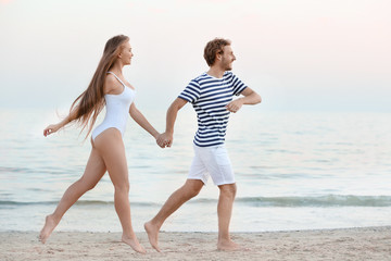 Happy young couple running on sea beach