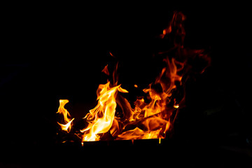 Flames of fire from burning coals in the grill late at night.