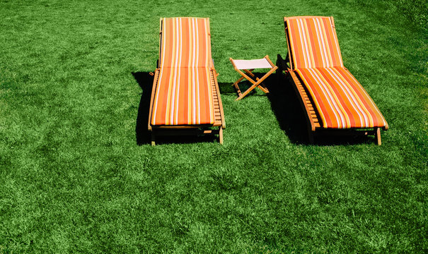Two Chaise Longue on the green grass, top view, summer vacation