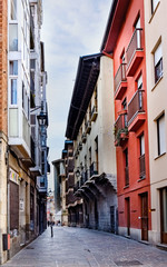 Narrow cobblestone street with facades of old houses with lots of color on the sides located in the old town of Vitoria Spain
