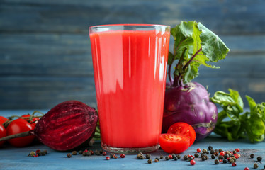 Glass of tasty red smoothie and vegetables on wooden table