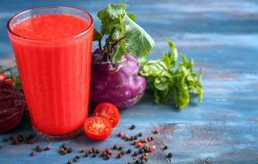 Glass of tasty red smoothie and vegetables on wooden table