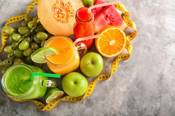 Glassware of tasty smoothies with  measuring tape on grey table. Diet concept