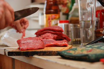 Butcher man cutting meat on the wooden board in the kitchen. Lifestyle