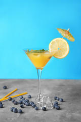 Fresh summer cocktail in glass on grey table against color background