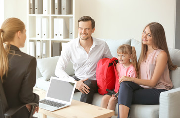 Young couple and their daughter meeting with headmistress at school