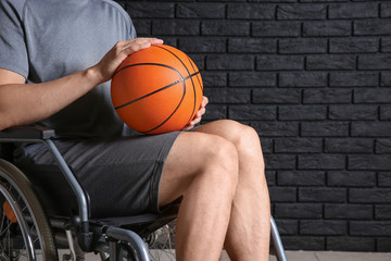 Young basketball player sitting in wheelchair against dark brick wall