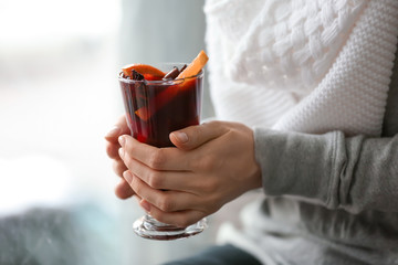 Woman holding glass cup of delicious mulled wine