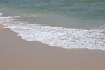 Diagonal close up of wet sand and soft wave use for summer background with place for text