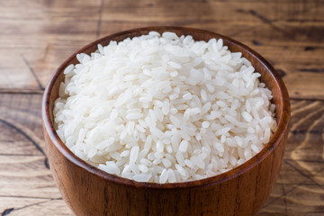 Fototapeta na wymiar White rice grits in wooden bowl on rustic wooden background.