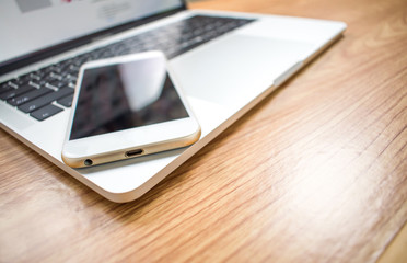 Close up. The man put the phone and the computer on the wood table in the room.