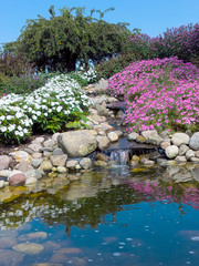 Fototapeta na wymiar waterfall in summer rock garden with water reflection