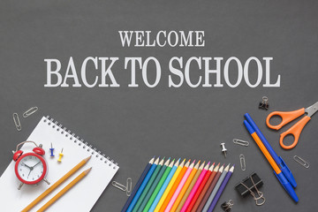 School supplies on black board background. inscription welcome back to school.