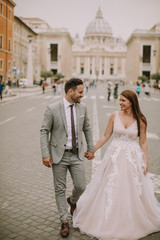 Fototapeta premium Young wedding couple by Saint Peter cathedral in Vatican