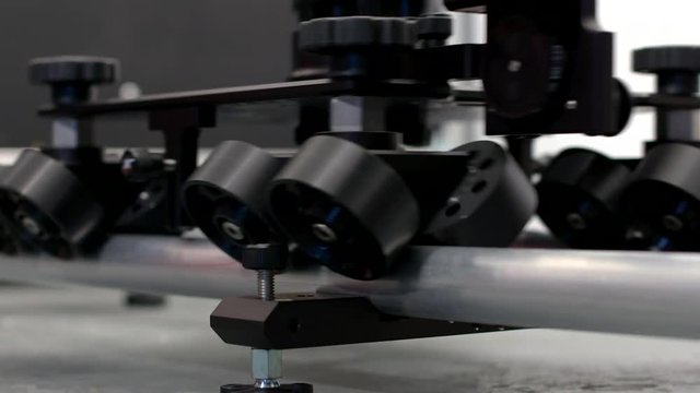 Rubber wheels rolling across scaff pole speed rail as part of a camera slider dolly system.
