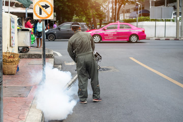Men run fog to eliminate mosquitoes to prevent dengue and Zika virus.