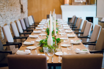 Rustic wedding decoration, table setting, floral and green plant arrangements indoors in the restaurant.