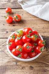 Cherry tomatoes red in ceramic bowl on wooden background