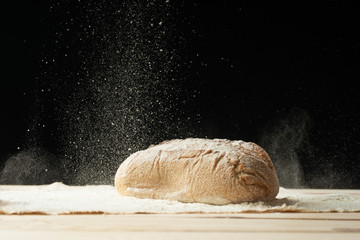 Fresh bread on the table close up in a scattering of flour. Fresh bread on the kitchen table. A healthy diet and a traditional bakery concept.