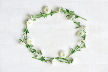 Wreath of white flowers on white wooden background