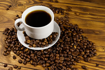 Cup of coffee and roasted coffee beans on wooden table