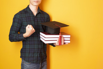 University man is happy with graduation on yellow background