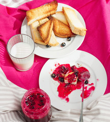 Delicious toasts bread with homemade currant jam on bright crimson tablecloth