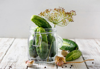 Preserved cucumbers in glass jar with dill and garlic on  table