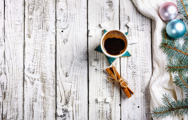 Cup of hot coffee with sugar and cinnamon on old wooden table with spruce branches.