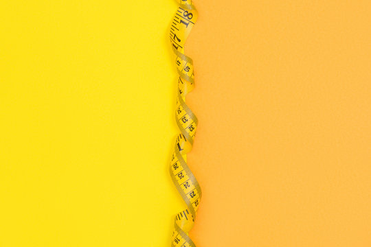 Half yellow half orange background with empty space devided with yellow tape measure