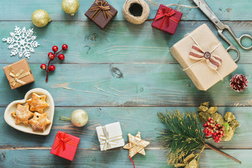 A frame of Christmas gifts box, cookies, Christmas decorations on a green wooden table. Top view, copy space. Flat lay.