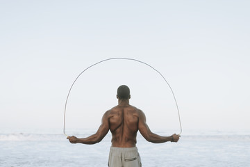 Fit man jumping rope at the beach