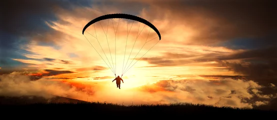 Vitrage gordijnen Luchtsport Paragliding in wolken bij zonsondergang.