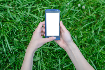 Woman holding smartphone with white empty touchscreen in hands over background of grass
