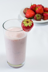 Glass of strawberry flavoured yogurt with fresh strawberries on plate. Concept of healthy nutrition