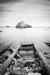 Black and white photo of sea and rocks, long exposure.