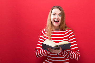 Naklejka premium Young woman with a book on a red background