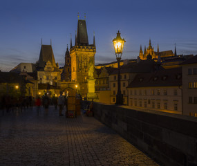 Fototapeta na wymiar View from Charles Bridge on Mala Strana bridge tower with glowing street lamp nad Prague Castle at night, dark blue sky