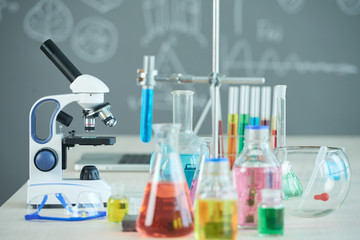 Microscope, test tube and various reagents on table in chemistry class