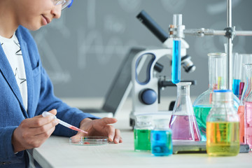 Fototapeta premium High school student putting red substance in petri dish