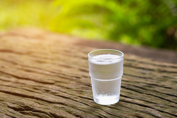 Clean drinking water in clear glass on wooden floor with soft light.