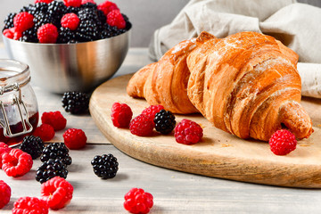Breakfast at the European hotel: coffee with milk and croissants, jam and fresh raspberries and blackberries on a wooden table. on the Cup inscription in French (mocha coffee, coffeewith milk)