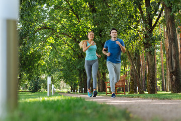Obraz premium Sport culture. Happy fit couple doing cardio activities while jogging together in the park