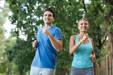 Healthy hobby. Delighted sportive couple smiling while enjoying sports activities together