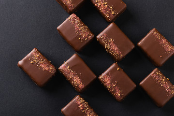 Luxury handmade bonbons decorated with pink salt on black background