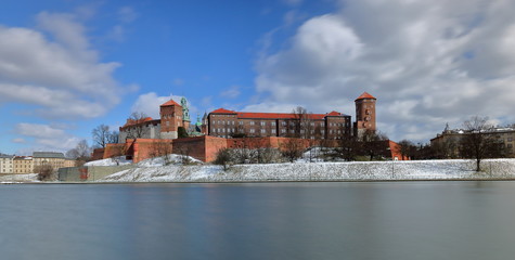 Wawel castle in Krakow, Poland, view from opposite Vistula river bank, winter, little snow on embankment, wonderful clouds in motion in blue sky