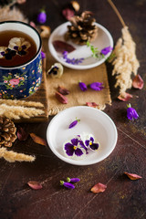 Fototapeta na wymiar Herbal tea: pansies, petals, edible flowers, on a light background