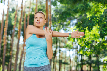 Sports exercise. Serious sporty woman moving her hand while doing an exercise