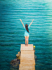 Fototapeta na wymiar Young beautiful brunette girl on the pier of Preveli Beach (Palm Beach), Preveli, Crete (Greece)