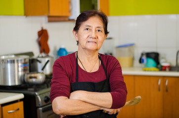 Senior lady cook from home holding a wooden spoon, concept of housewife or home cooking